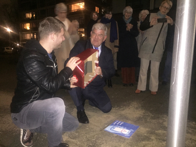 845200 Afbeelding van de onthulling, door burgemeester mr. J.H.C. van Zanen, van de stoeptegel met de tekst Deze buurt ...